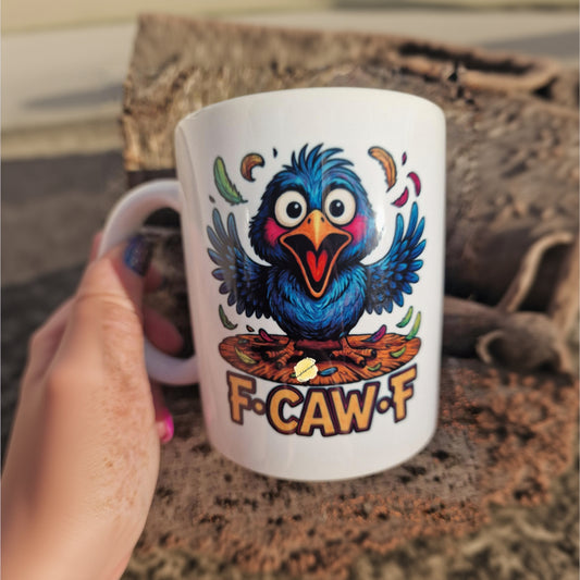Mug with a colorful bird design and 'F-CAW-F' text held by a person.